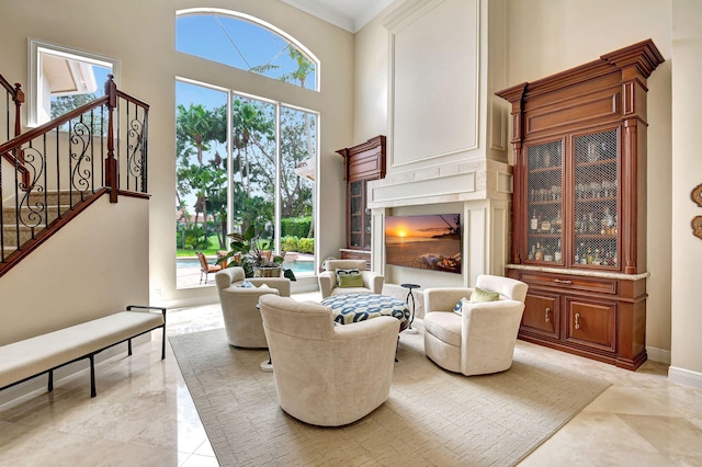 living room with a towering ceiling, crown molding, and plenty of natural light