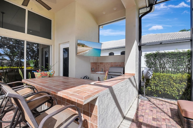 view of patio / terrace with area for grilling, ceiling fan, exterior bar, and an outdoor kitchen