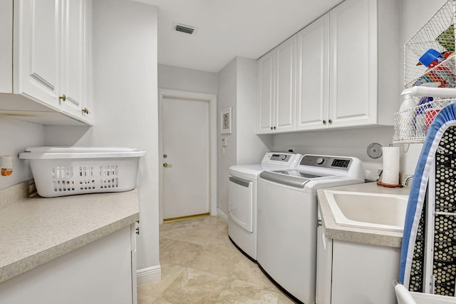 washroom with sink, washing machine and dryer, and cabinets