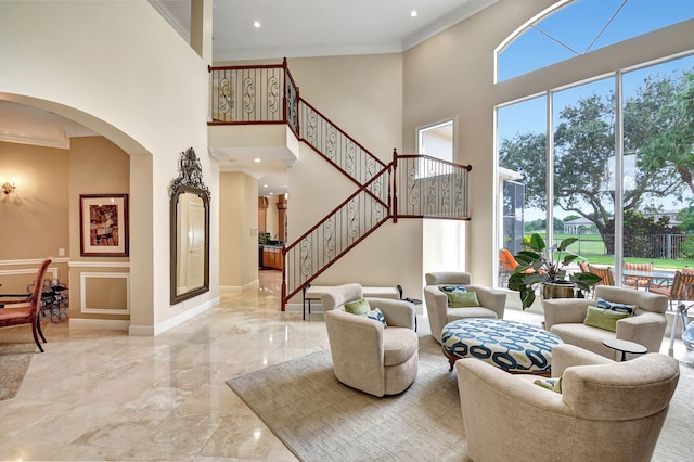 living room with a towering ceiling and ornamental molding