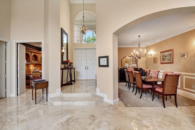 entrance foyer with a towering ceiling, an inviting chandelier, and ornamental molding