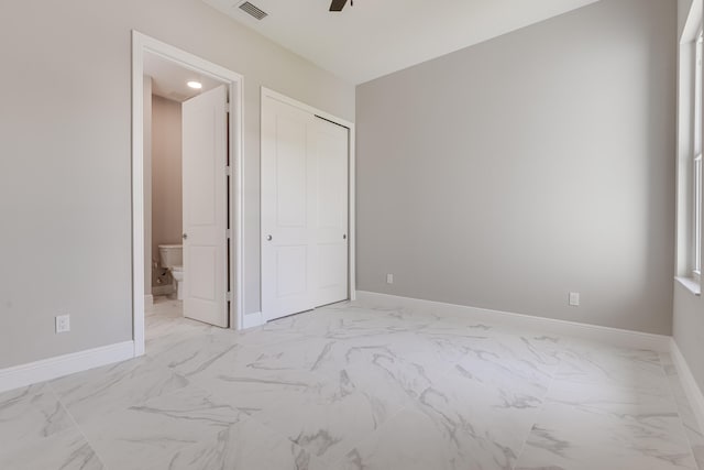 unfurnished bedroom featuring a closet, ensuite bath, and ceiling fan