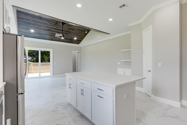 kitchen featuring lofted ceiling, ceiling fan, a kitchen island, white cabinetry, and stainless steel refrigerator