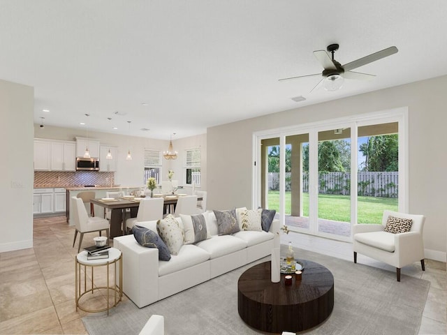 tiled living room featuring ceiling fan with notable chandelier