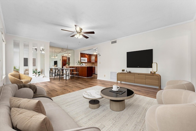 living room with ceiling fan, ornamental molding, and hardwood / wood-style floors