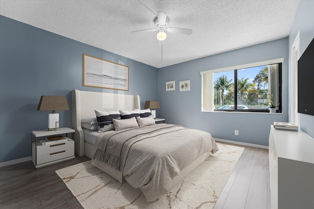 bedroom with a textured ceiling, dark wood-type flooring, and ceiling fan