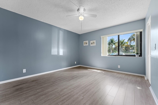 empty room featuring a textured ceiling, ceiling fan, and wood-type flooring