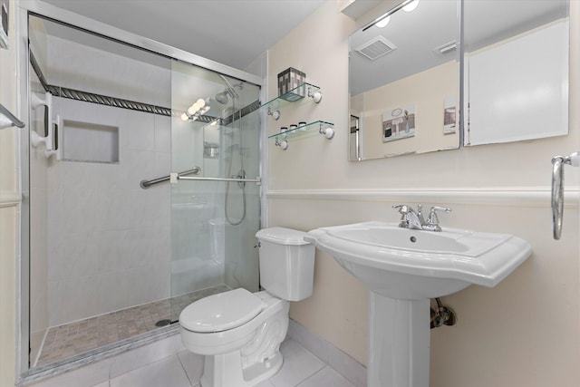 bathroom featuring tile patterned floors, a shower with shower door, and toilet