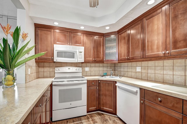 kitchen with white appliances, tasteful backsplash, light hardwood / wood-style floors, and sink