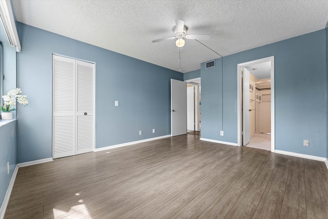 unfurnished bedroom featuring hardwood / wood-style flooring, ceiling fan, a textured ceiling, and a closet