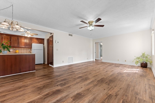 unfurnished living room with ceiling fan with notable chandelier, dark wood-type flooring, a textured ceiling, and ornamental molding