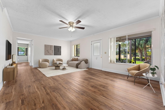 living room featuring hardwood / wood-style floors, ceiling fan, crown molding, and a textured ceiling