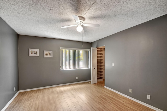 spare room with a textured ceiling, ceiling fan, and light hardwood / wood-style floors