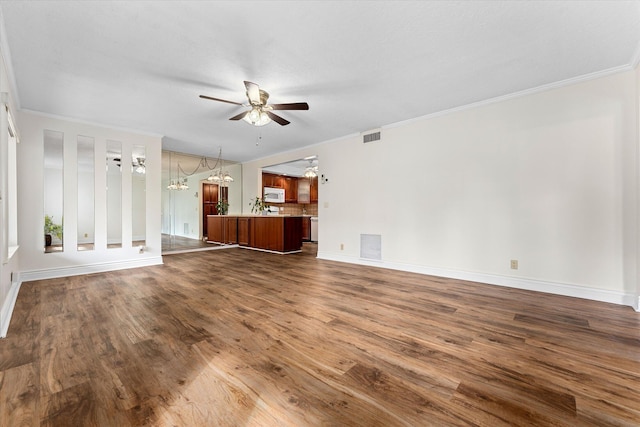 unfurnished living room with ceiling fan with notable chandelier, dark wood-type flooring, and ornamental molding