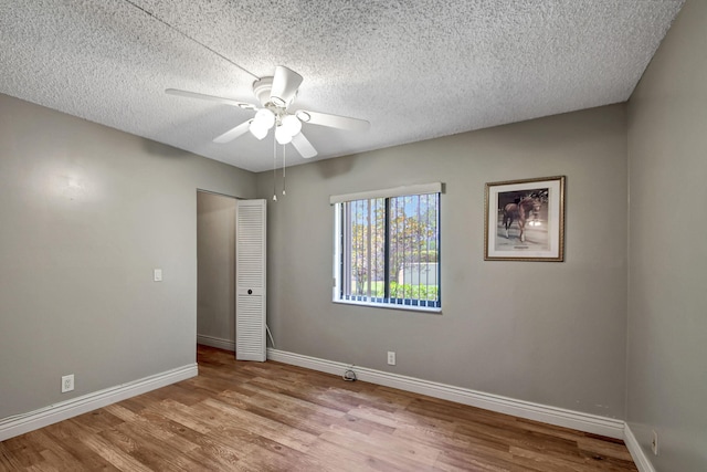 empty room featuring ceiling fan, light hardwood / wood-style flooring, and a textured ceiling