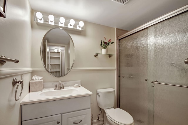 bathroom featuring vanity, a shower with shower door, and toilet