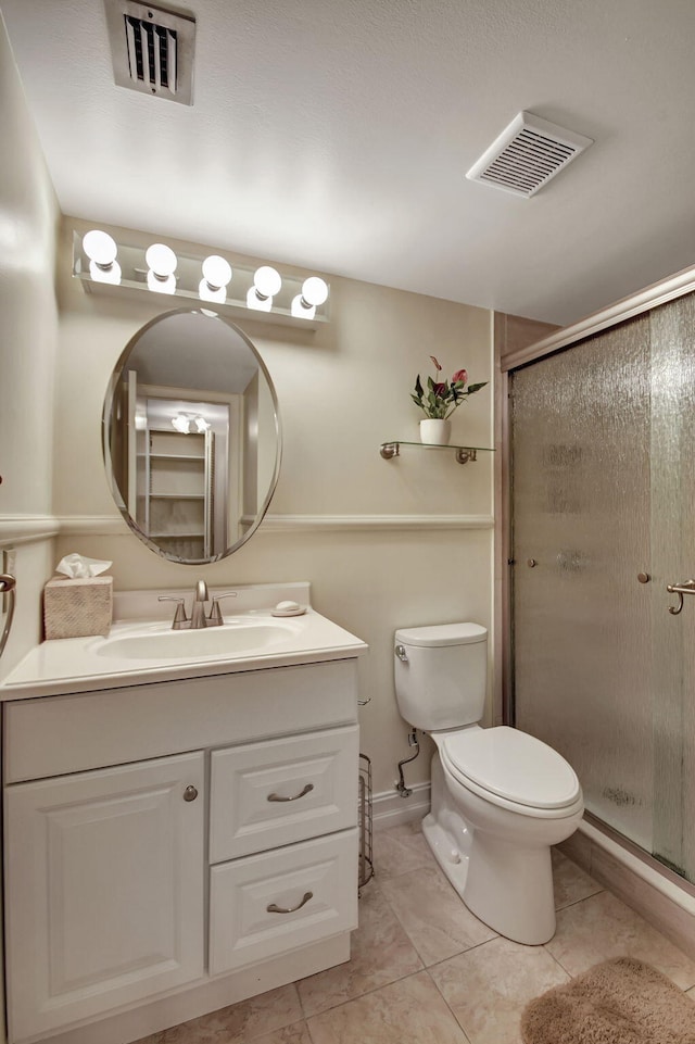 bathroom featuring toilet, tile patterned floors, walk in shower, and vanity