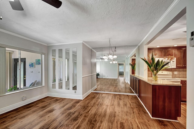 interior space with ceiling fan with notable chandelier, a textured ceiling, hardwood / wood-style flooring, and crown molding