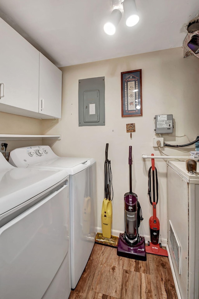 laundry area featuring electric panel, cabinets, independent washer and dryer, and hardwood / wood-style flooring