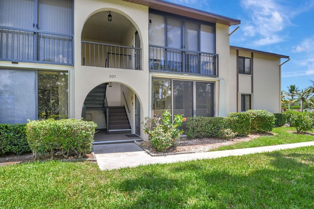 entrance to property featuring a balcony and a lawn