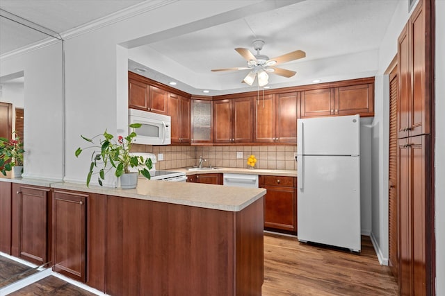 kitchen featuring tasteful backsplash, white appliances, light hardwood / wood-style floors, sink, and kitchen peninsula