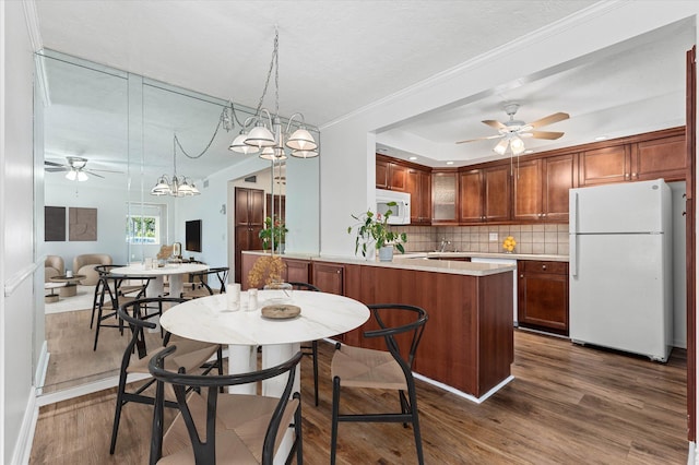 kitchen with decorative backsplash, white appliances, kitchen peninsula, and dark wood-type flooring