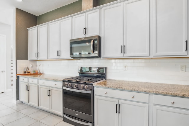 kitchen with light stone counters, tasteful backsplash, light tile patterned flooring, white cabinetry, and appliances with stainless steel finishes