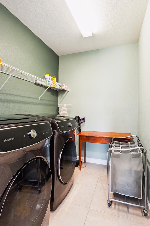 clothes washing area featuring independent washer and dryer, light tile patterned floors, and a textured ceiling