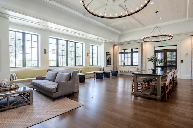 living room featuring dark wood-type flooring, a chandelier, beamed ceiling, and crown molding