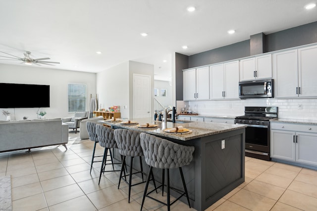 kitchen featuring white cabinetry, appliances with stainless steel finishes, a center island with sink, and a kitchen breakfast bar