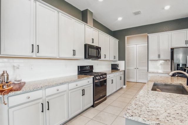 kitchen with white cabinetry, sink, black appliances, light tile patterned floors, and decorative backsplash