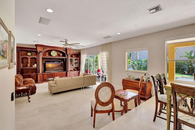 living room featuring ceiling fan and a textured ceiling