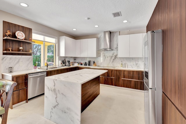 kitchen featuring appliances with stainless steel finishes, wall chimney exhaust hood, white cabinetry, and a kitchen island