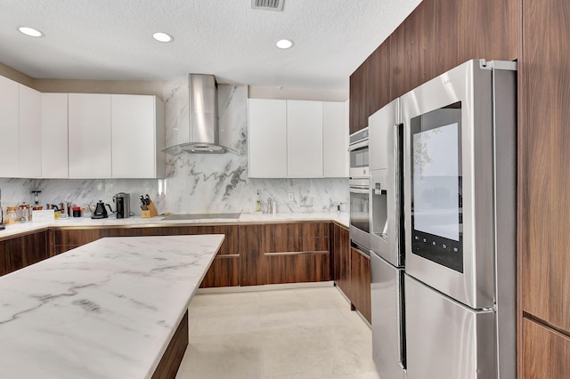 kitchen with wall chimney range hood, decorative backsplash, white cabinetry, and stainless steel appliances