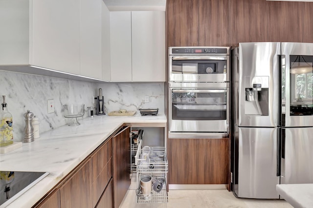 kitchen with white cabinetry, light stone countertops, tasteful backsplash, and appliances with stainless steel finishes