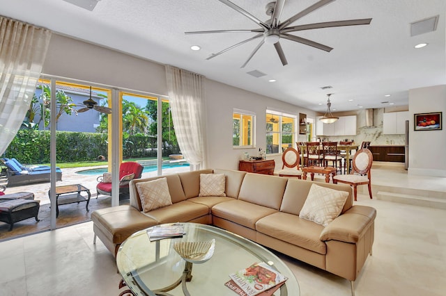 living room with ceiling fan, a healthy amount of sunlight, and a textured ceiling