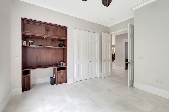 unfurnished bedroom featuring built in desk, ornamental molding, a closet, and ceiling fan