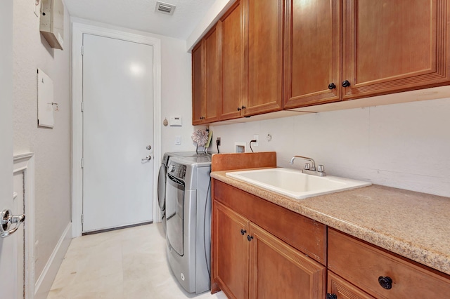 clothes washing area featuring sink, separate washer and dryer, and cabinets