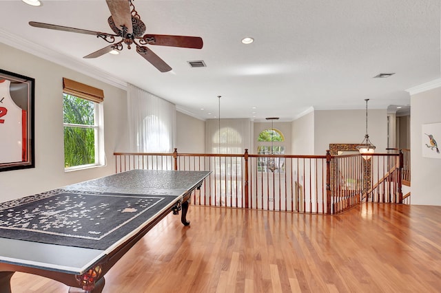 recreation room featuring ornamental molding, a textured ceiling, hardwood / wood-style flooring, and ceiling fan