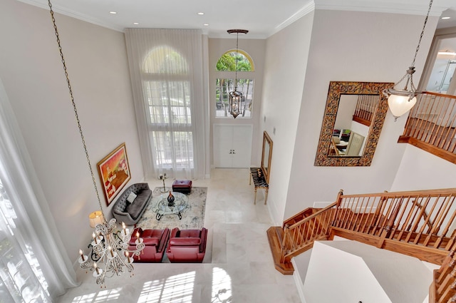 foyer featuring an inviting chandelier, ornamental molding, and a high ceiling