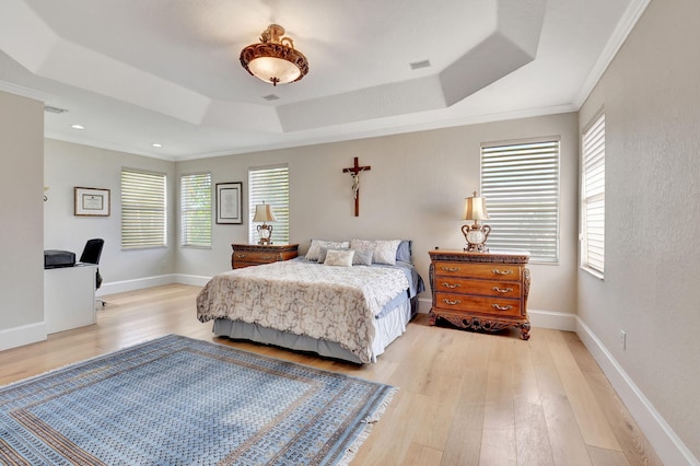 bedroom featuring ornamental molding, light hardwood / wood-style flooring, and a tray ceiling