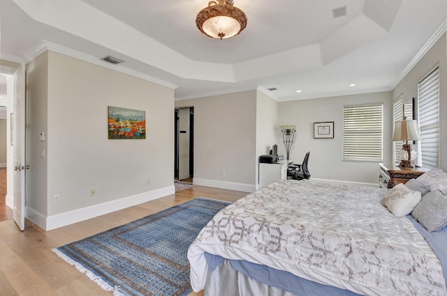 bedroom featuring ornamental molding, light hardwood / wood-style floors, and a raised ceiling