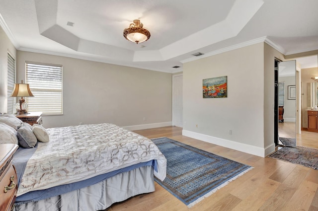 bedroom with crown molding, light wood-type flooring, and a raised ceiling