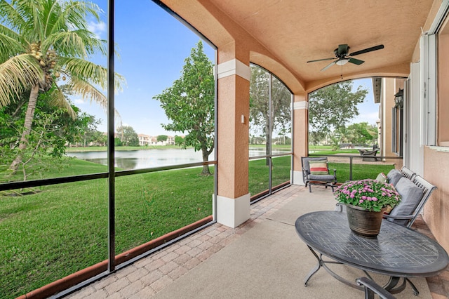 sunroom featuring ceiling fan, a water view, and vaulted ceiling