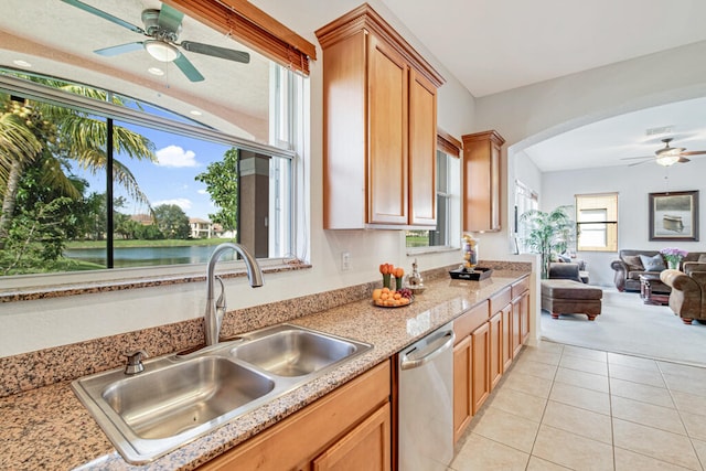 kitchen with dishwasher, a water view, light tile patterned floors, and sink