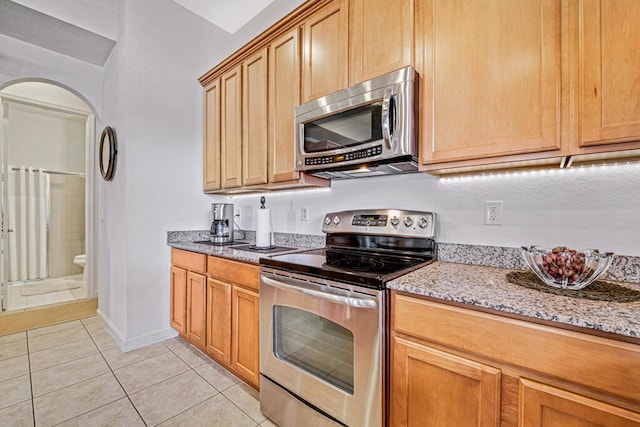 kitchen featuring light tile patterned flooring, light stone counters, and appliances with stainless steel finishes