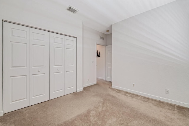 unfurnished bedroom featuring light colored carpet and a closet