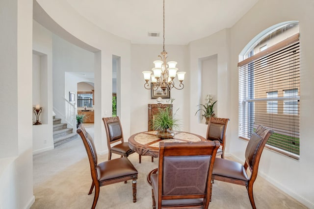 dining space with light carpet and a chandelier