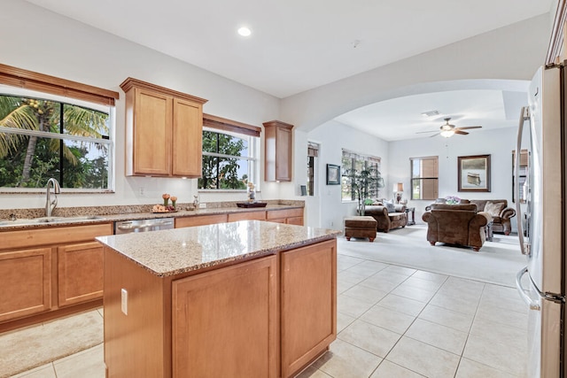 kitchen with a center island, light stone counters, a wealth of natural light, and sink