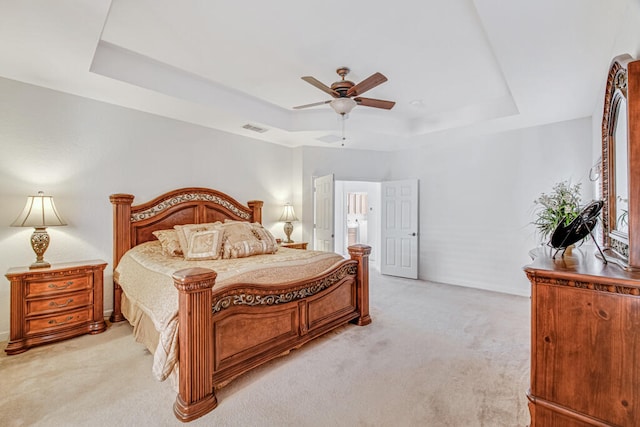 carpeted bedroom featuring ceiling fan and a tray ceiling